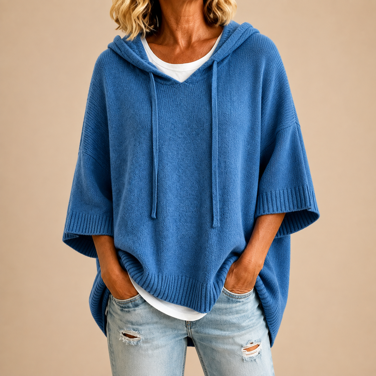Poncho en maille bleue MIRELLA™ de Danoir Paris avec capuche, porté avec détails visibles en tissu doux et confortable.