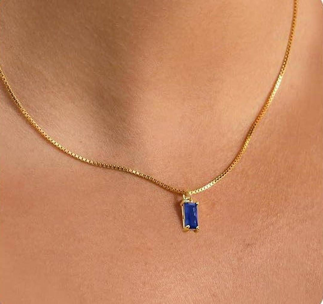 Collier minimaliste en saphir de Danoir Paris, pendentif élégant en forme de goutte, porté sur une chaîne fine en acier.