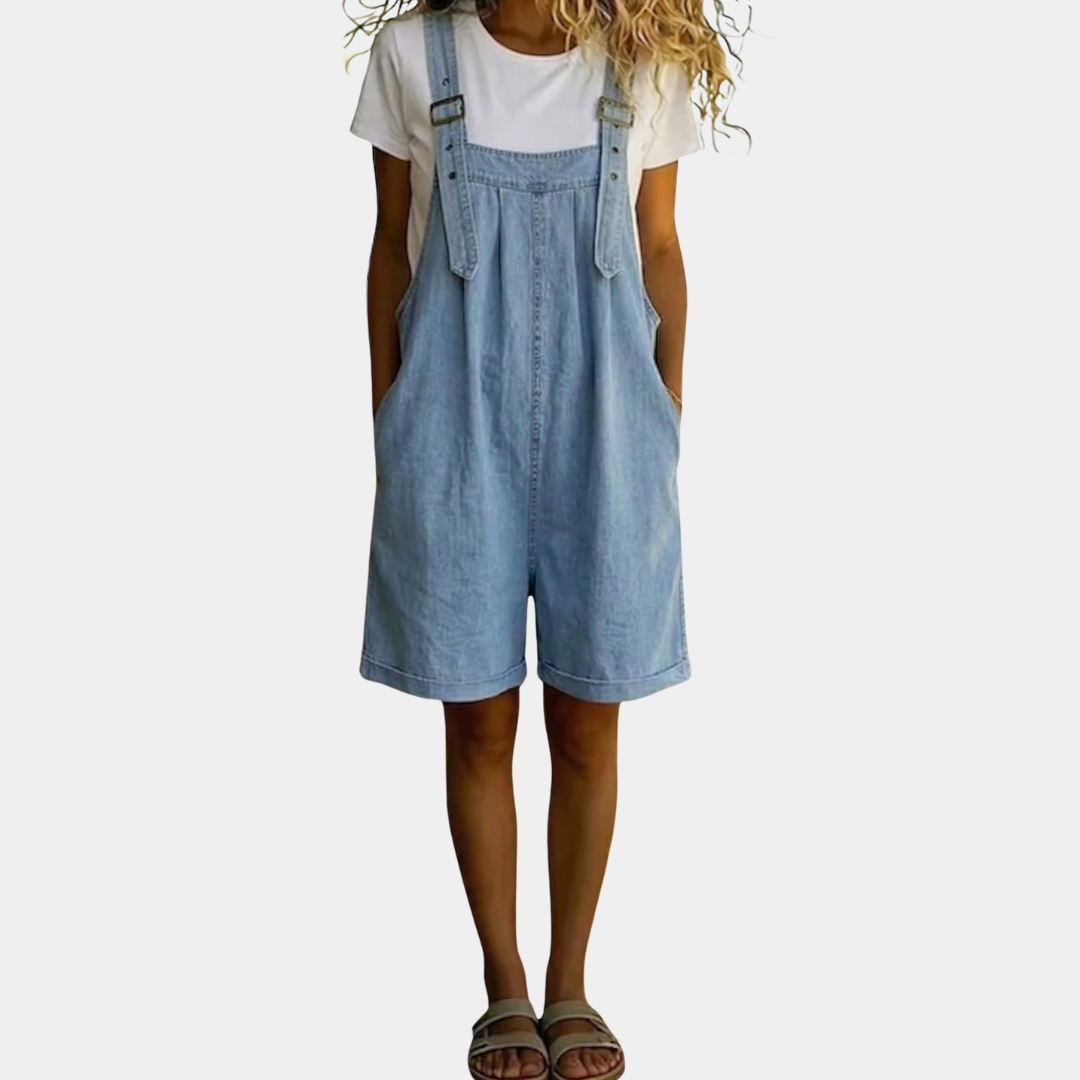 Salopette courte en denim bleu clair avec fini vintage délavé, conçue par Danoir Paris, portée avec poches et bretelles ajustables.