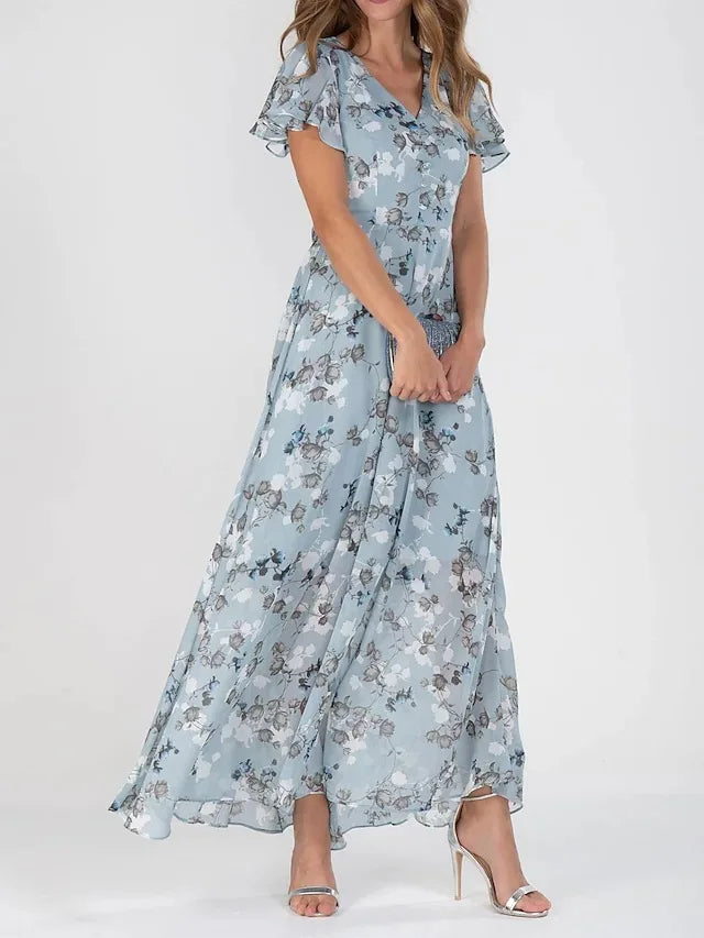 Robe maxi fleurie élégante Danoir Paris, tissu fluide avec motifs floraux, porté avec manches longues et décolleté en V.