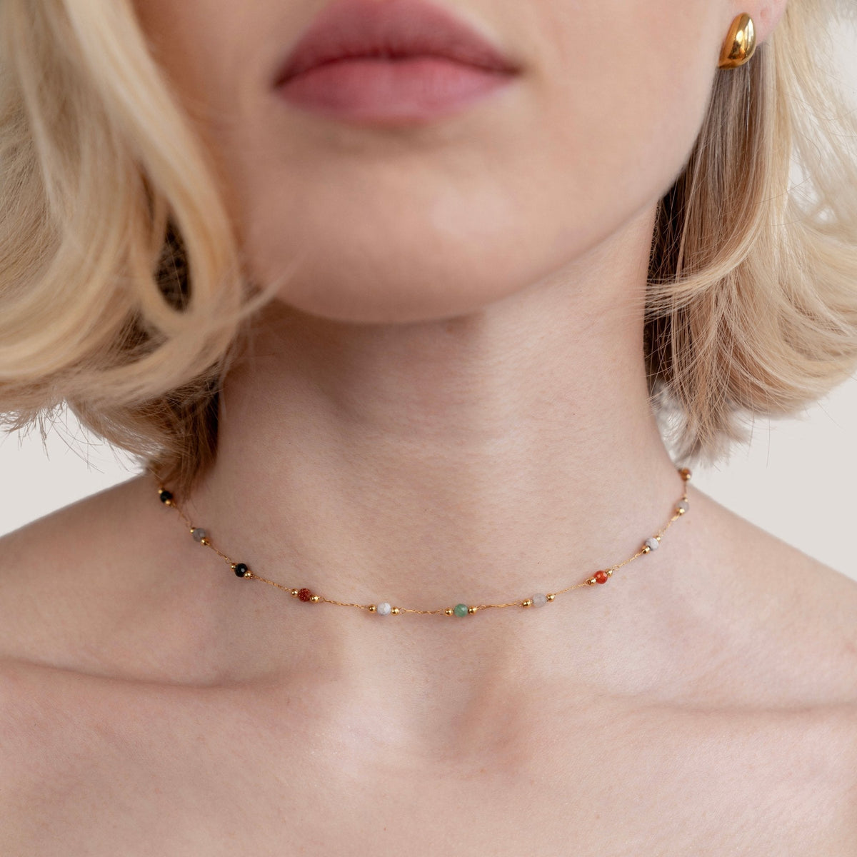 Collier minimaliste avec pierre de Danoir Paris, chaîne fine avec pendentif en pierre élégante, porté sur un fond neutre.