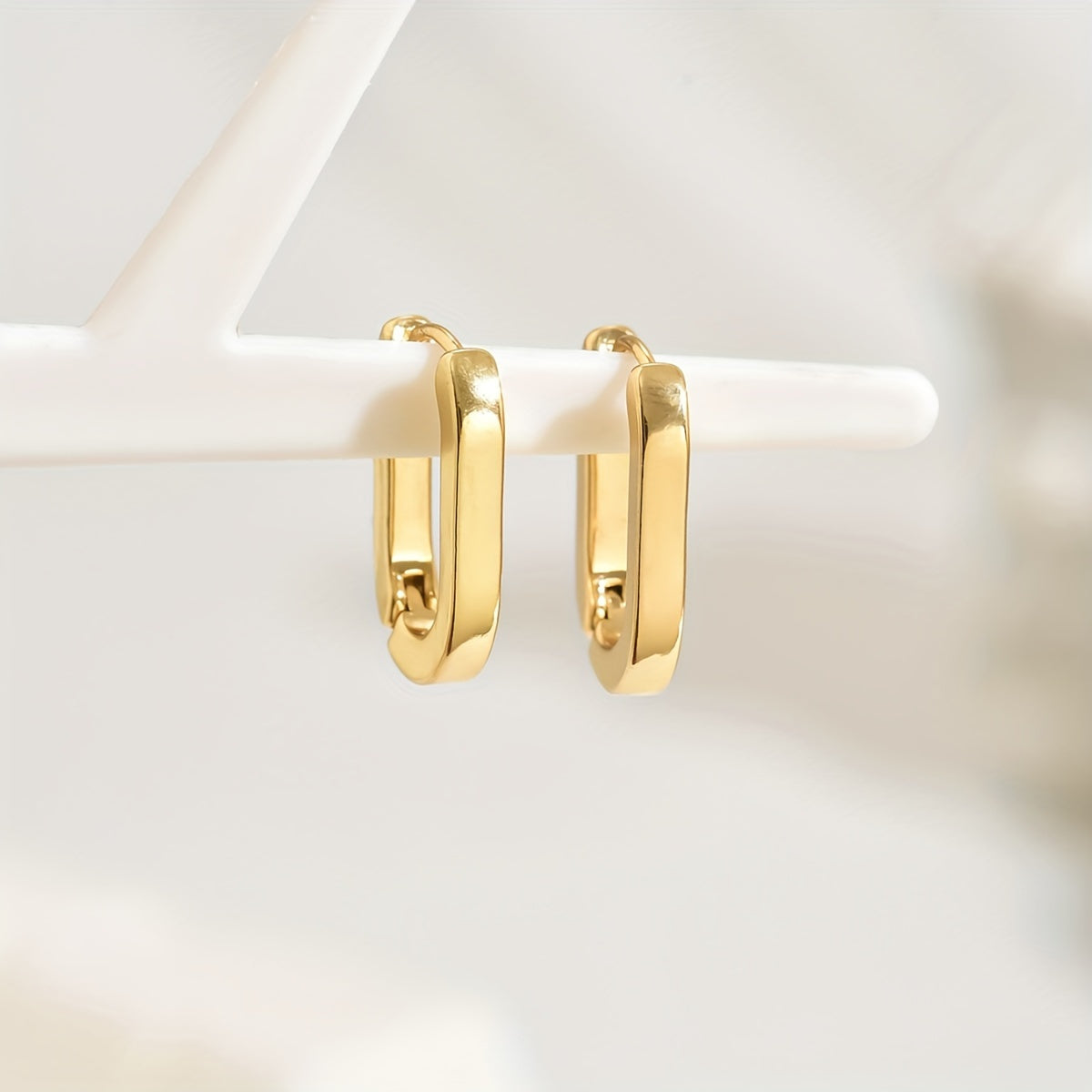 Boucles d'oreilles créoles géométriques élégantes de Danoir Paris, en métal doré, avec design moderne et sophistiqué.