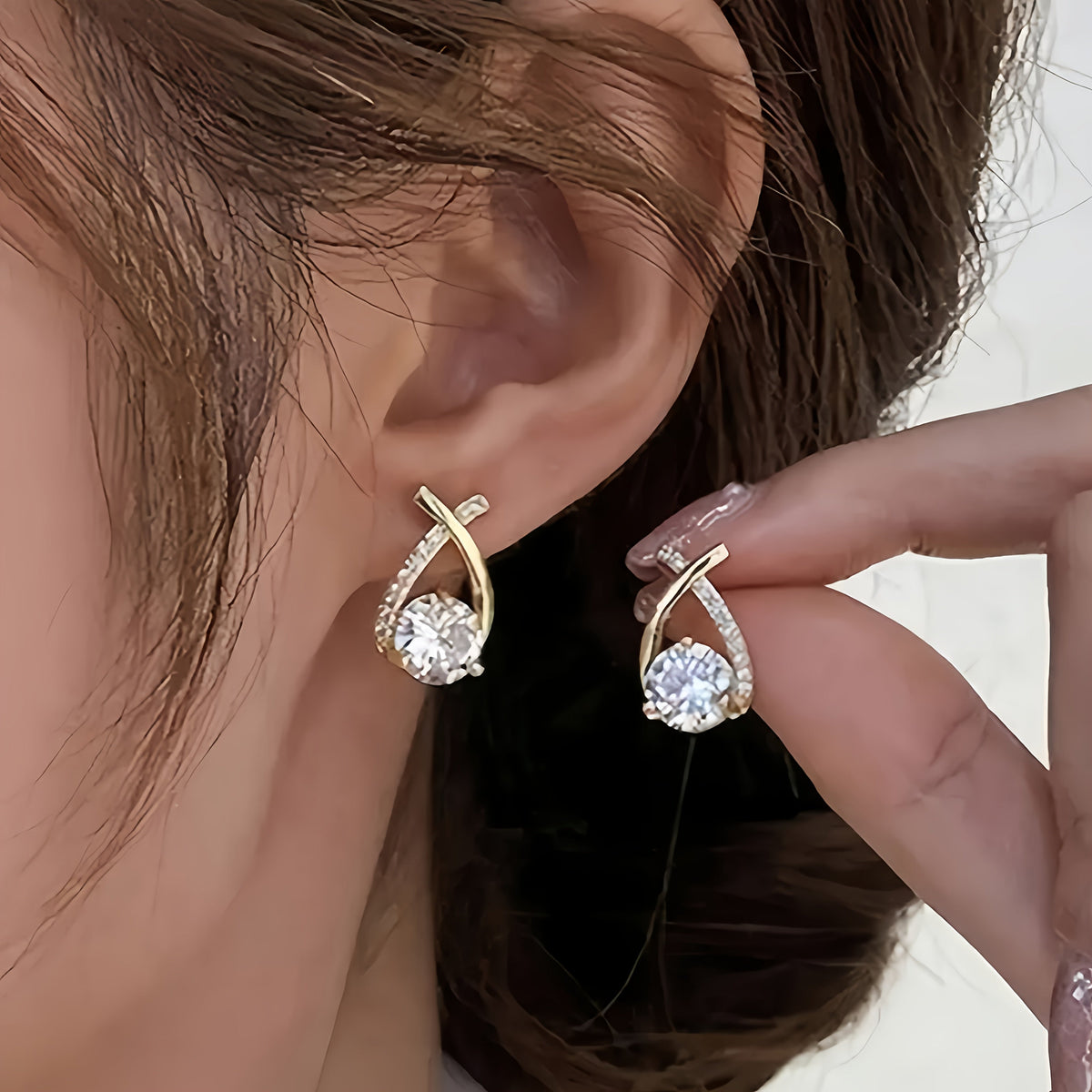 Boucles d'oreilles en puce Danoir Paris avec croix dorée et zirconiums, élégantes et modernes, visibles en gros plan.