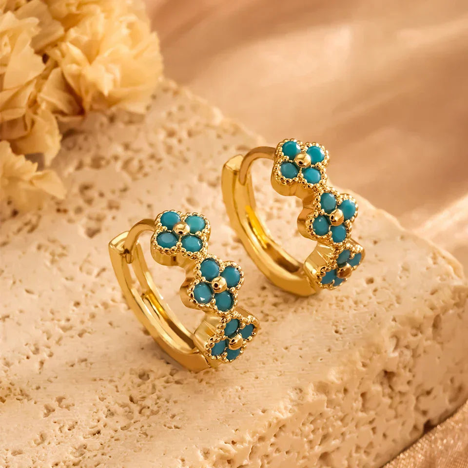 Boucles d'oreilles créoles Danoir Paris avec fleurs turquoise, bijoux élégants en métal coloré et design floral.