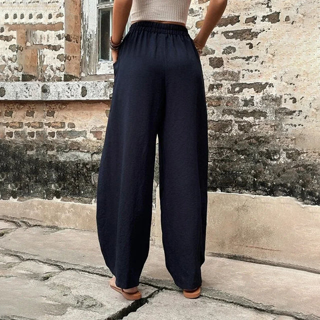 Pantalons fluides Vanna de Danoir Paris, en tissu léger, avec coupe élégante et ceinture à la taille, porté avec une blouse blanche.