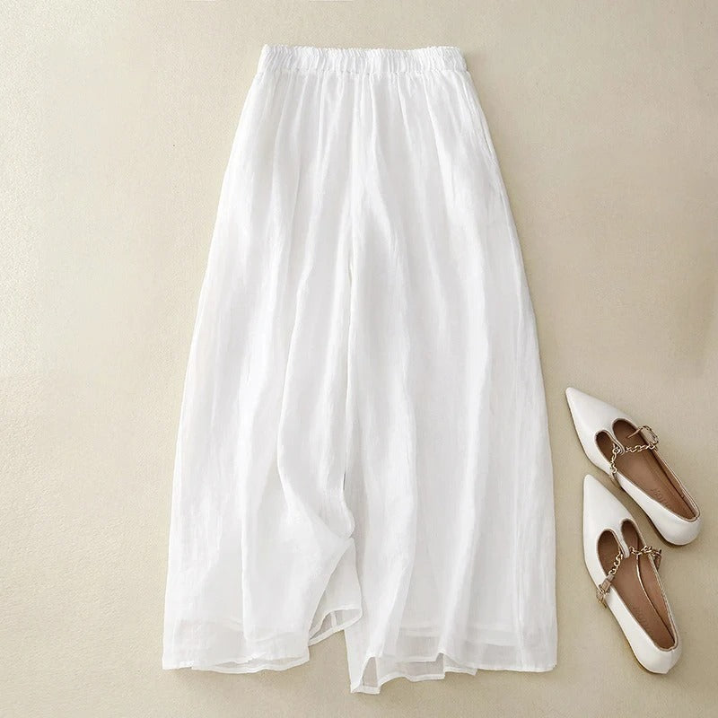 Pantalons en lin élégants Nicolé de Danoir Paris, coupe fluide et tissu léger, portés avec une blouse blanche.