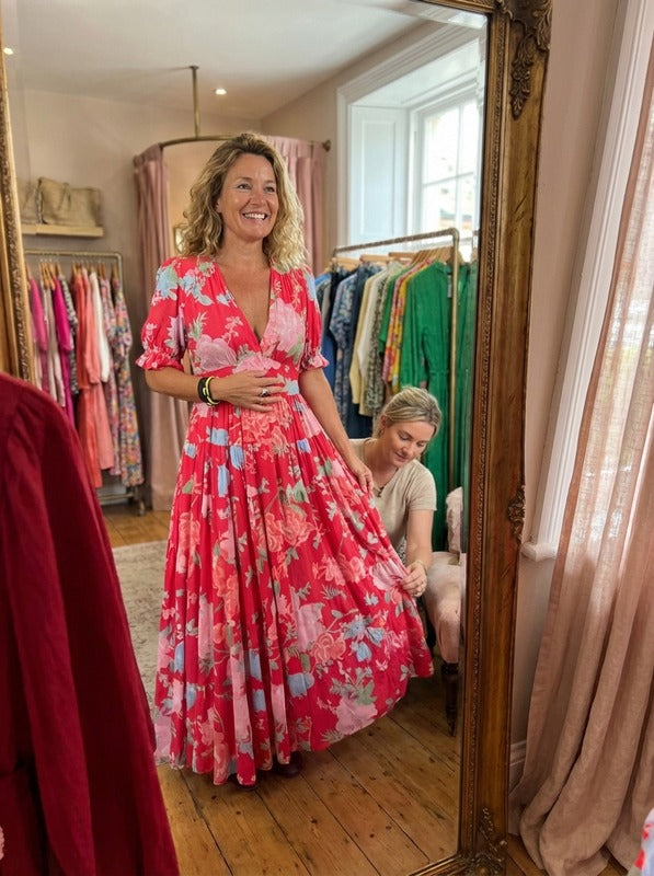 Robe florale élégante avec décolleté en V de la marque Danoir Paris, portée par une vendeuse devant un miroir.