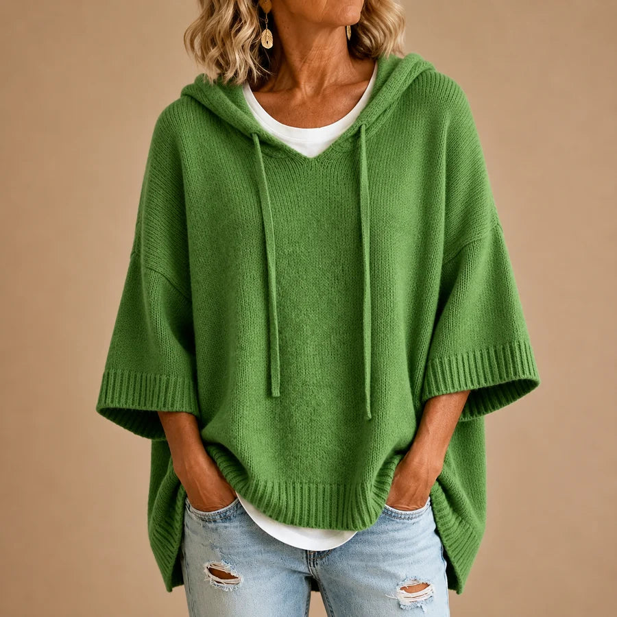 Poncho en tricot bleu marine avec capuche de Danoir Paris, texture douce et confortable, porté en extérieur.