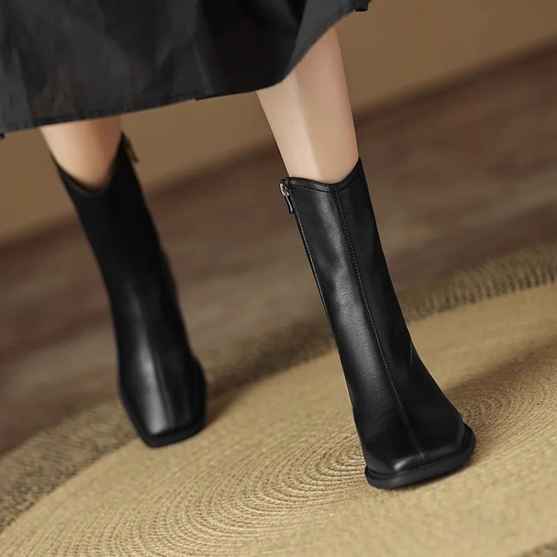 Bottines Danoir Paris Joséphine avec bout carré et talon bloc, en cuir noir, sur une surface en bois clair.