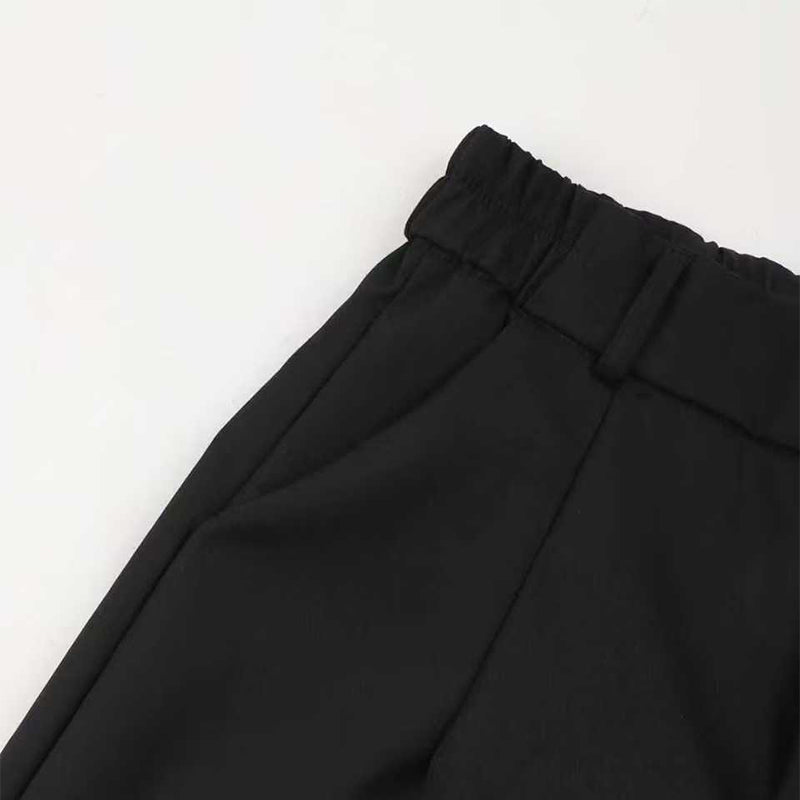Pantalon de costume taille haute pour femmes Danoir Paris, coupe élégante en tissu noir, porté avec une blouse blanche.