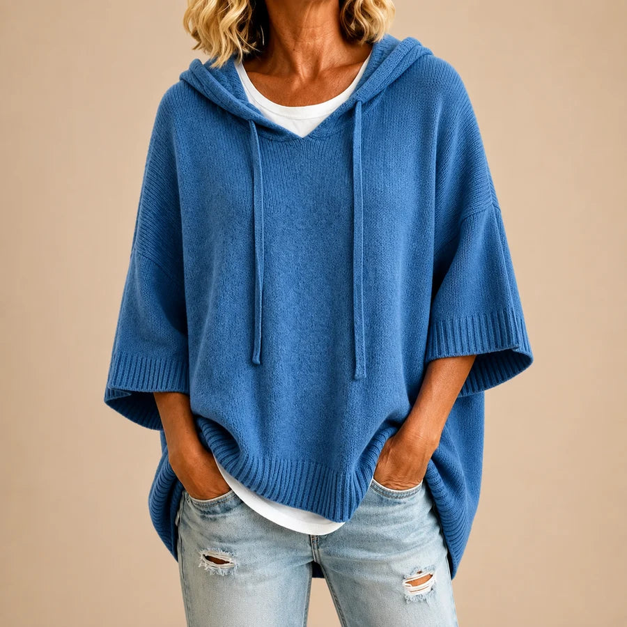 Poncho en tricot bleu marine avec capuche de la marque Danoir Paris, doux et chaud, porté en extérieur.