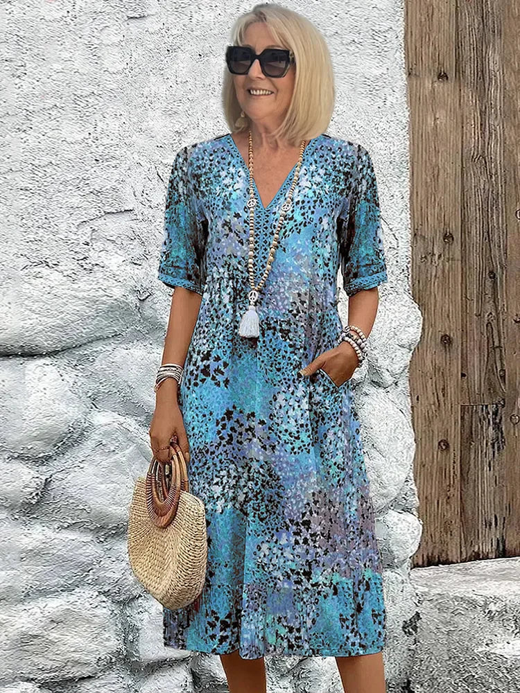 Robe midi éclatante Lina de Danoir Paris, tissu coloré et fluide, portée avec manches longues et décolleté élégant.