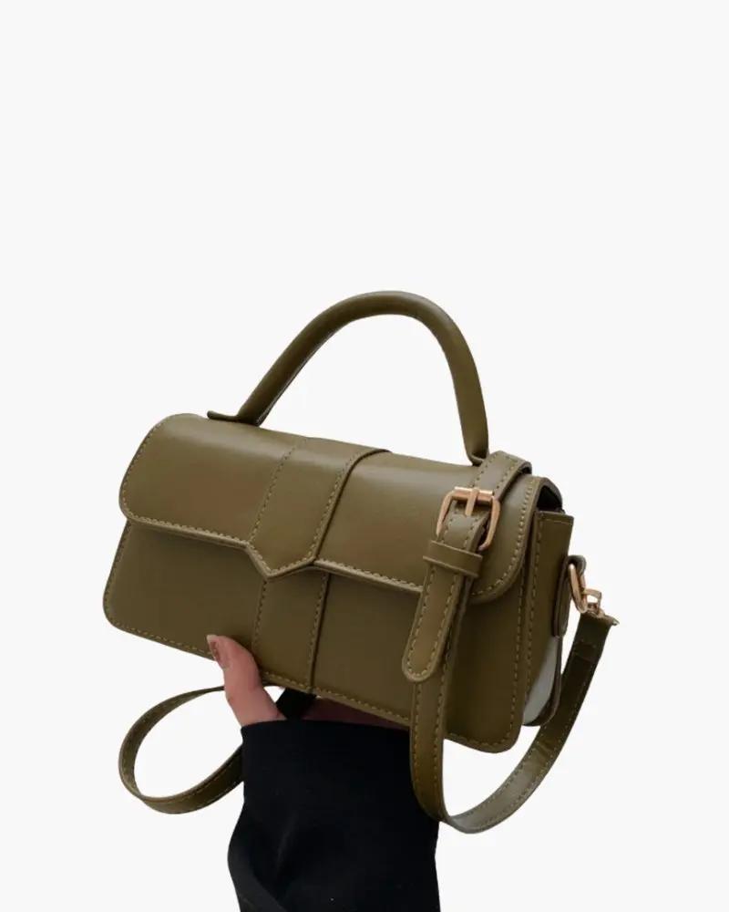Sac à main Paris de Danoir Paris, en cuir marron avec poignées et fermeture or, posé sur une surface en bois.