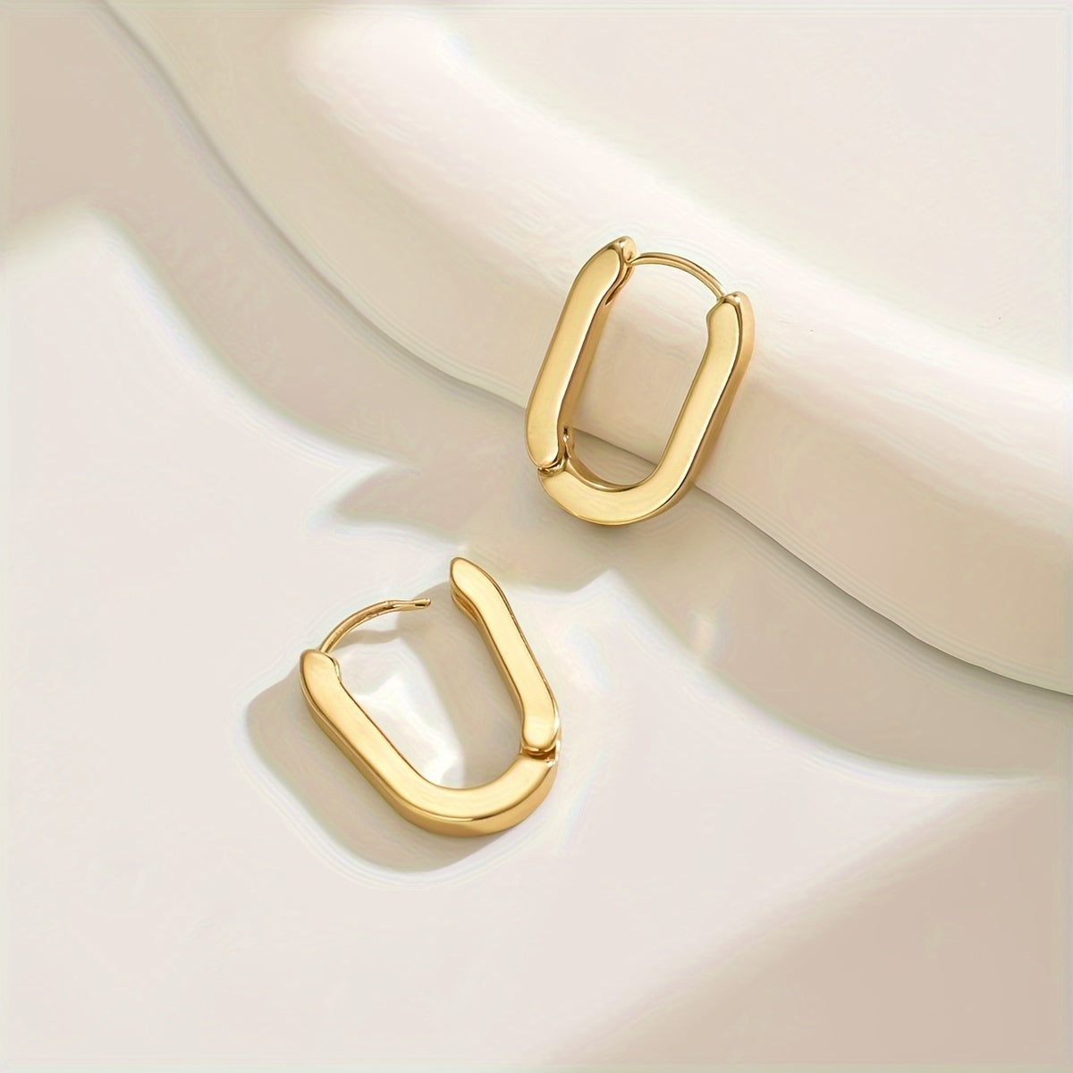 Boucles d'oreilles créoles élégantes de forme géométrique de la marque Danoir Paris, en métal doré.