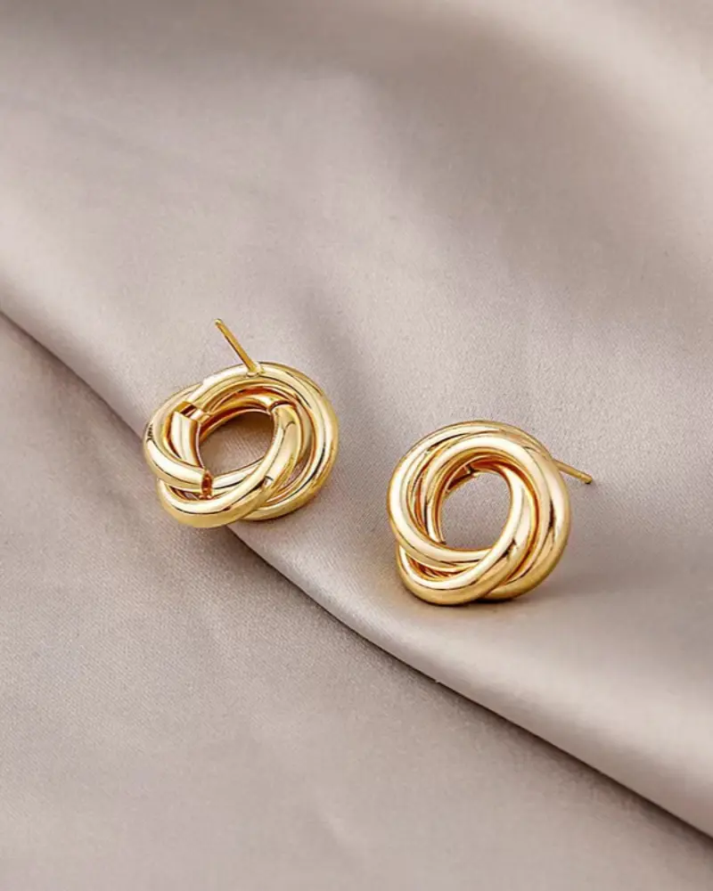 Boucles d'oreilles créoles Danoir Paris Aurelia Knot Studs en or avec motif torsadé, visibles sur fond blanc.