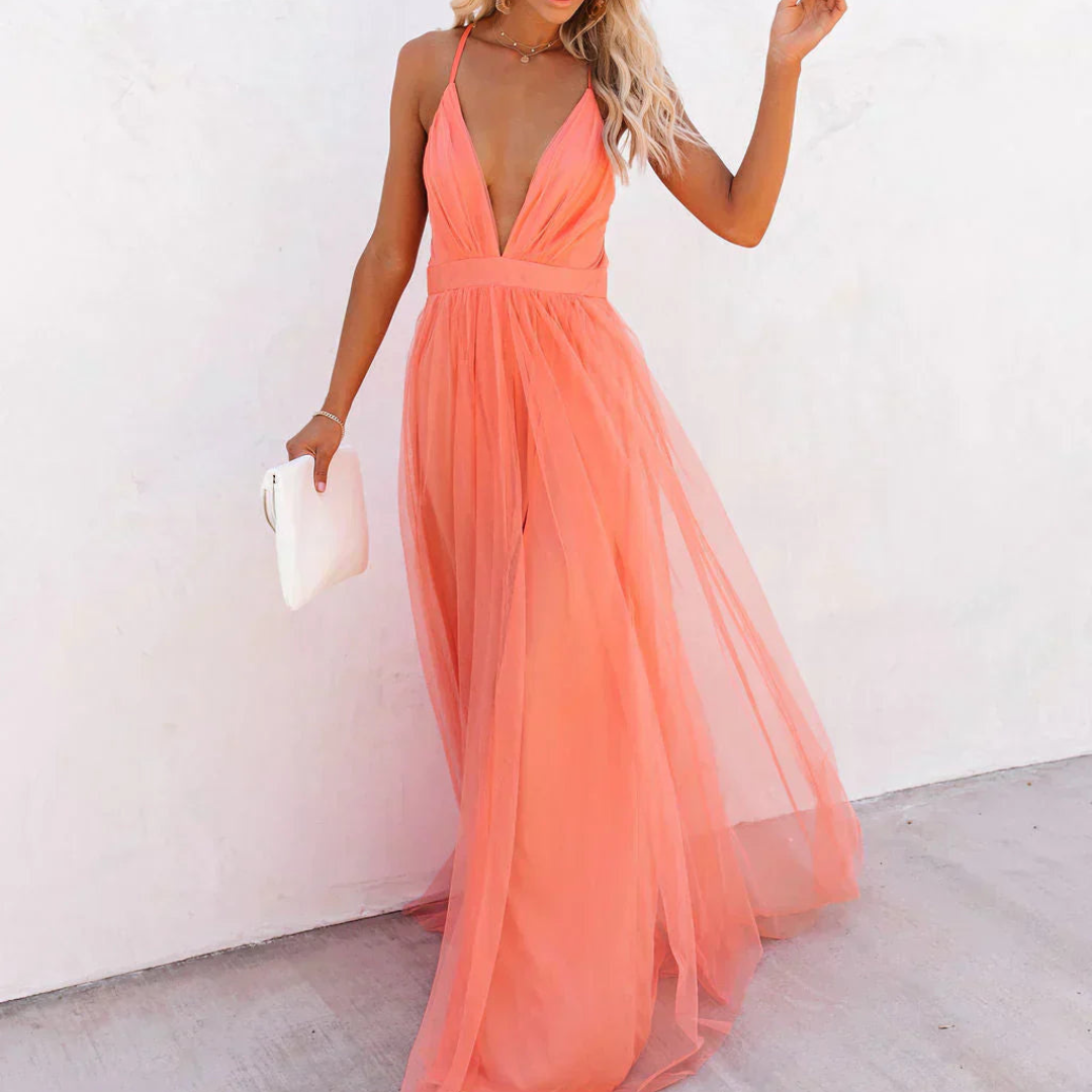 Robe maxi Danoir Paris couleur corail, longue et fluide, avec décolleté en V et détails élégants, portée dans un cadre lumineux.
