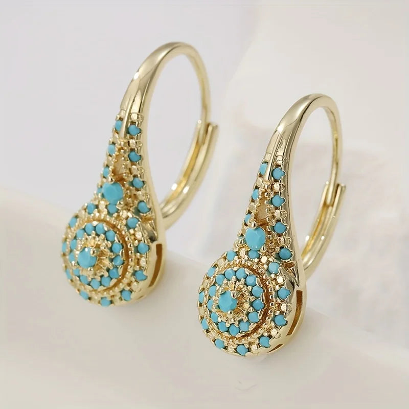 Boucles d'oreilles dorées avec fleurs turquoise de Danoir Paris, design élégant et artisanal, parfait pour une touche de couleur.