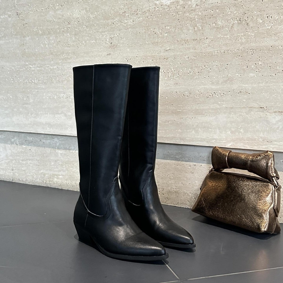 Bottes hautes Danoir Paris Aurélie avec bout pointu, en cuir noir, sur une modèle portant une tenue élégante.